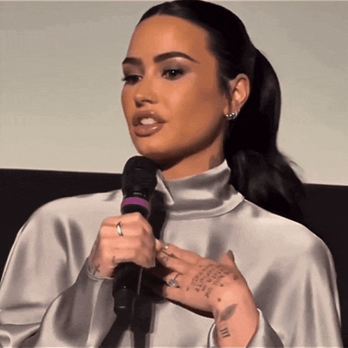 a woman speaking into a microphone with a tattoo on her hand that says iii