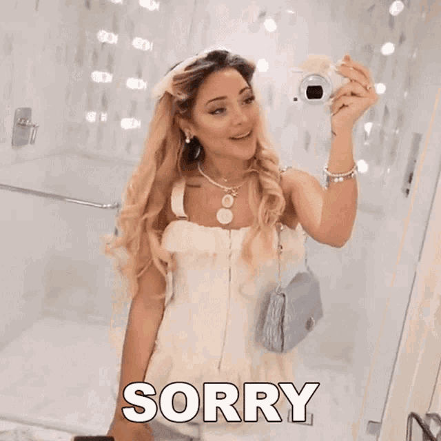 a woman in a white dress is taking a picture of herself in the mirror .