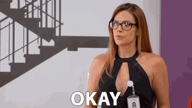 a woman wearing glasses and a name tag with the word okay on it