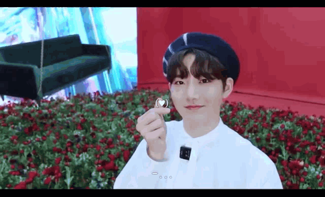 a young man wearing a beret and a white shirt is holding a heart shaped object in his hand .