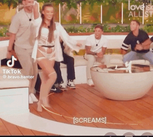 a group of people are sitting on a couch and a woman is dancing in front of them .