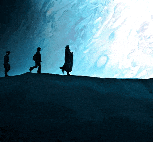 three people walking on a hill in the dark