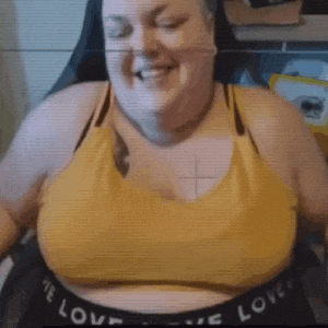 a woman is sitting in a chair with her eyes closed and smiling while wearing a yellow sports bra .