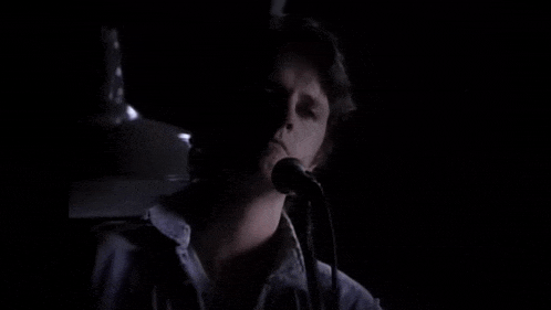 a man in a blue shirt is singing into a microphone .