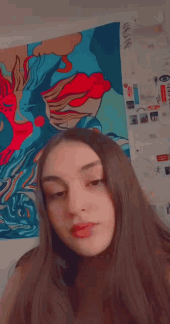 a woman is taking a selfie in front of a colorful tapestry that says ' usns ' on it