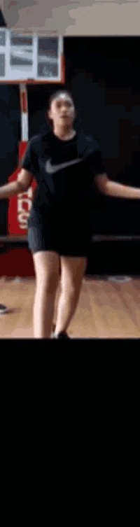 a woman wearing a nike shirt and shorts is dancing in a gym .