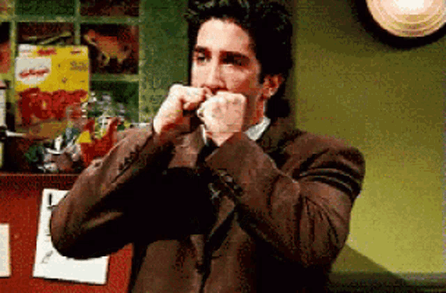 a man in a suit and tie is eating a box of kellogg 's cereal .