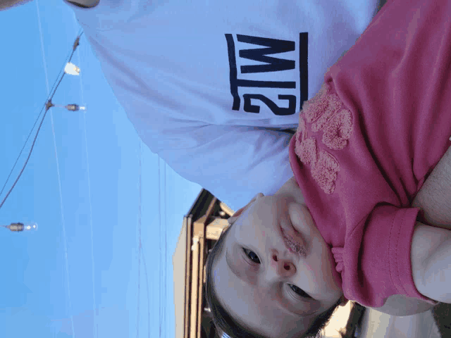 a man holding a baby wearing a shirt that says m2 on it