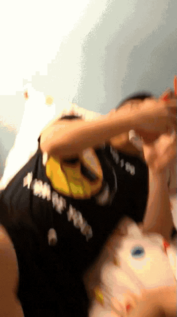 a person wearing a black shirt with a yellow smiley face and the letter s on it