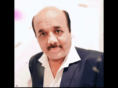 a bald man with a mustache wearing a suit and white shirt