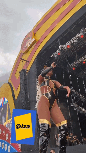 a woman in a swimsuit is standing on a stage with a yellow sign that says @iza