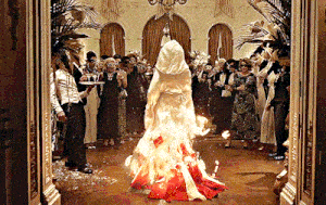 a woman in a white and red dress is burning in a room full of people