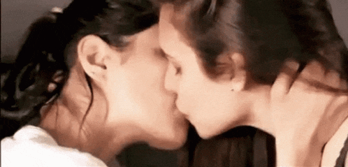 two women are kissing each other on the cheek in a close up .