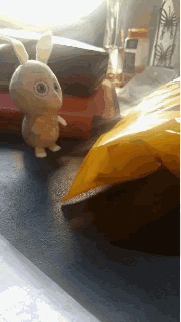 a stuffed bunny is standing next to a yellow bag