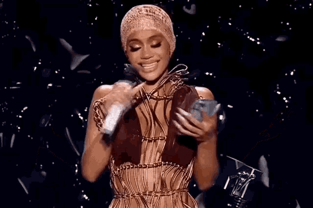 a woman in a dress is holding a microphone and a cell phone in her hands .