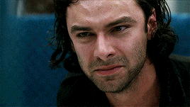 a man with long hair and a beard looks at the camera