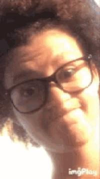 a close up of a woman wearing glasses and making a face .