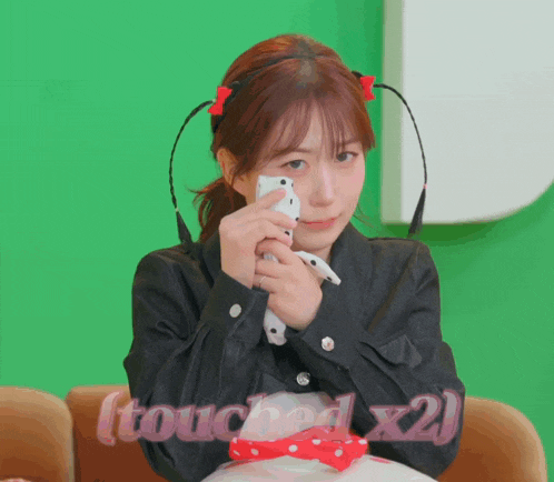 a girl holding a cell phone with the words touched x2 written below her