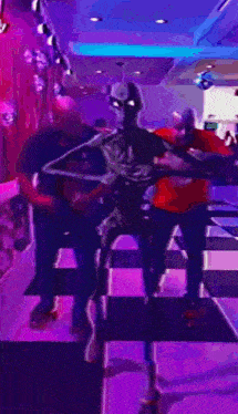 a group of people are dancing in a room with purple lighting