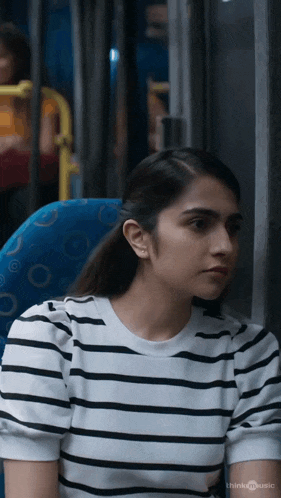 a woman in a striped shirt is sitting on a blue bus