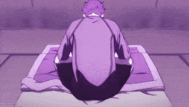 a man in a purple shirt sits on a purple mat
