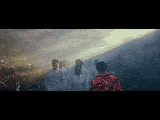 a group of people in white shirts are walking through a forest