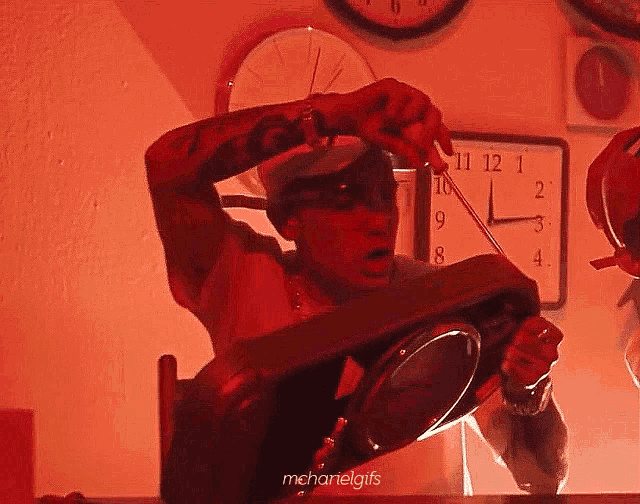 a man is looking at himself in a mirror in front of a wall clock that says 11 12 1 on it