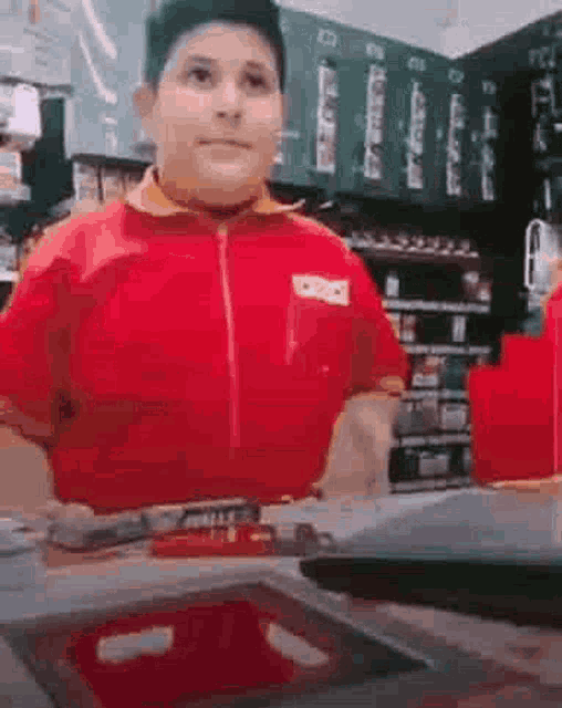 a boy in a red shirt is standing in a store .