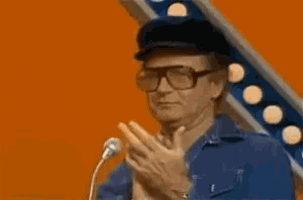 a man wearing glasses and a hat is giving an okay sign .