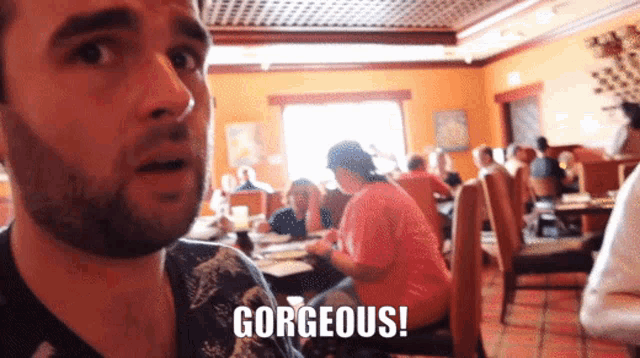 a man in a restaurant says gorgeous in front of people sitting at tables