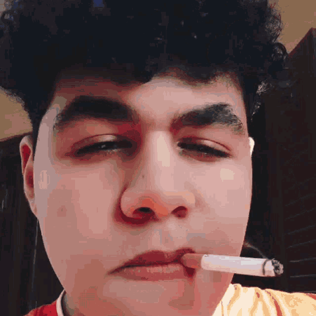 a young man with curly hair smoking a cigarette