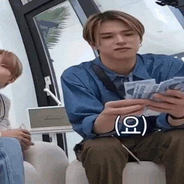 a man is sitting on a couch holding a pile of money .