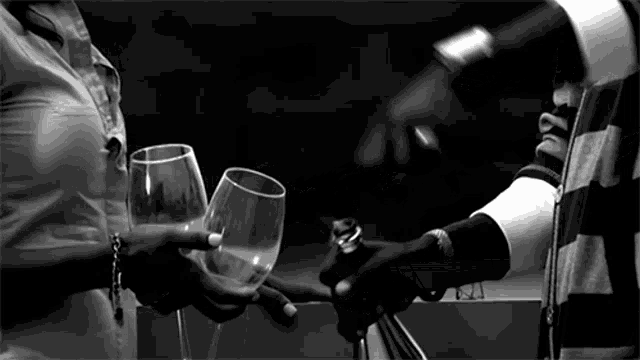 a black and white photo of a woman holding a glass of wine