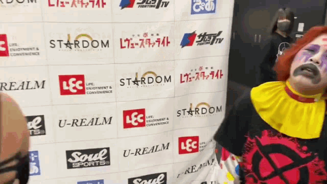 a man in a clown costume is standing in front of a wall that says stardom