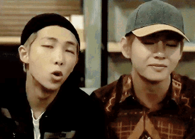 a man wearing a baseball cap is sitting next to another man