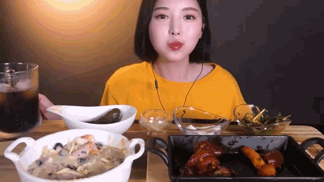 a woman in a yellow shirt is sitting at a table eating a variety of food