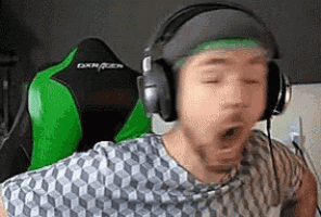 a man wearing headphones and a green headband is yawning while sitting in a green chair .