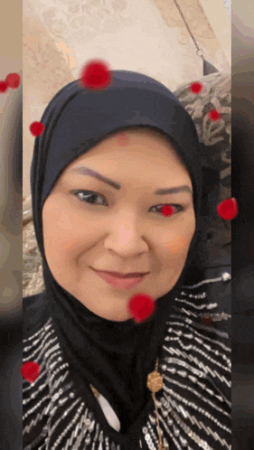 a woman wearing a hijab is smiling with red hearts around her face