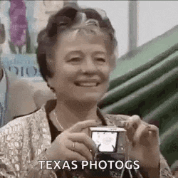 a woman is smiling while taking a picture of herself with a camera .