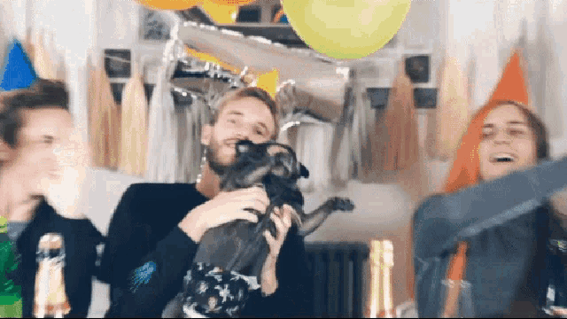a man is holding a small dog in his arms while a woman holds a bottle of champagne