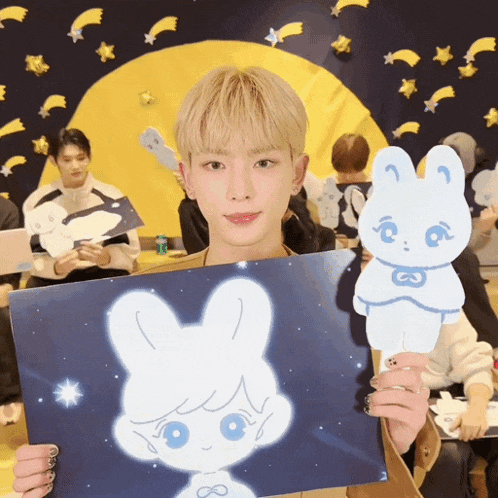 a young man holds a drawing of a bunny with the number 8 on it