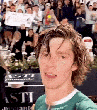 a man taking a selfie in front of a sign that says asti on it
