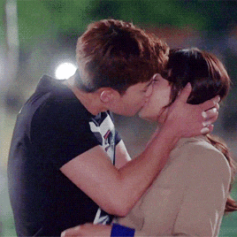 a man and a woman are kissing and the man is wearing a black shirt