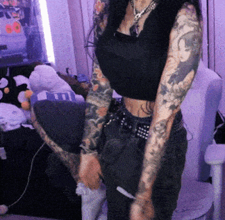 a woman with a lot of tattoos on her arms holds a remote control