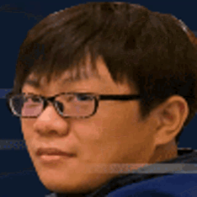 a man wearing glasses and a blue jacket is looking at the camera .