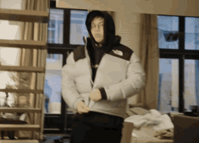 a man wearing a north face jacket is standing in a room