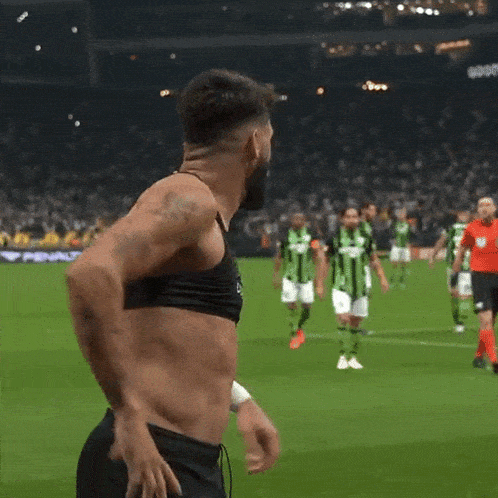 a shirtless man wearing a catapult chest strap stands on a soccer field