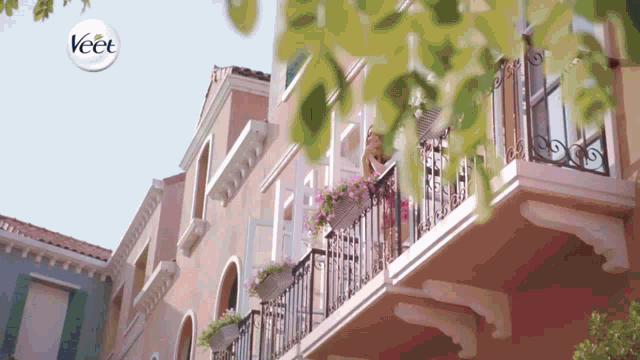a woman is standing on a balcony with a veet logo above her