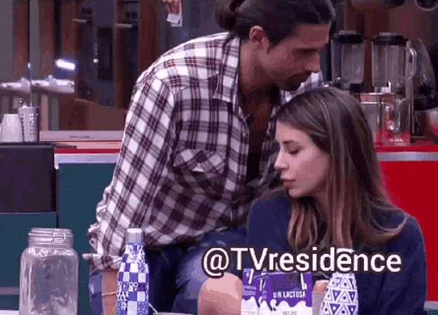 a man in a plaid shirt is kissing a woman in front of a bottle of sin lactosa milk