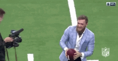 a man in a suit throwing a football on a field .